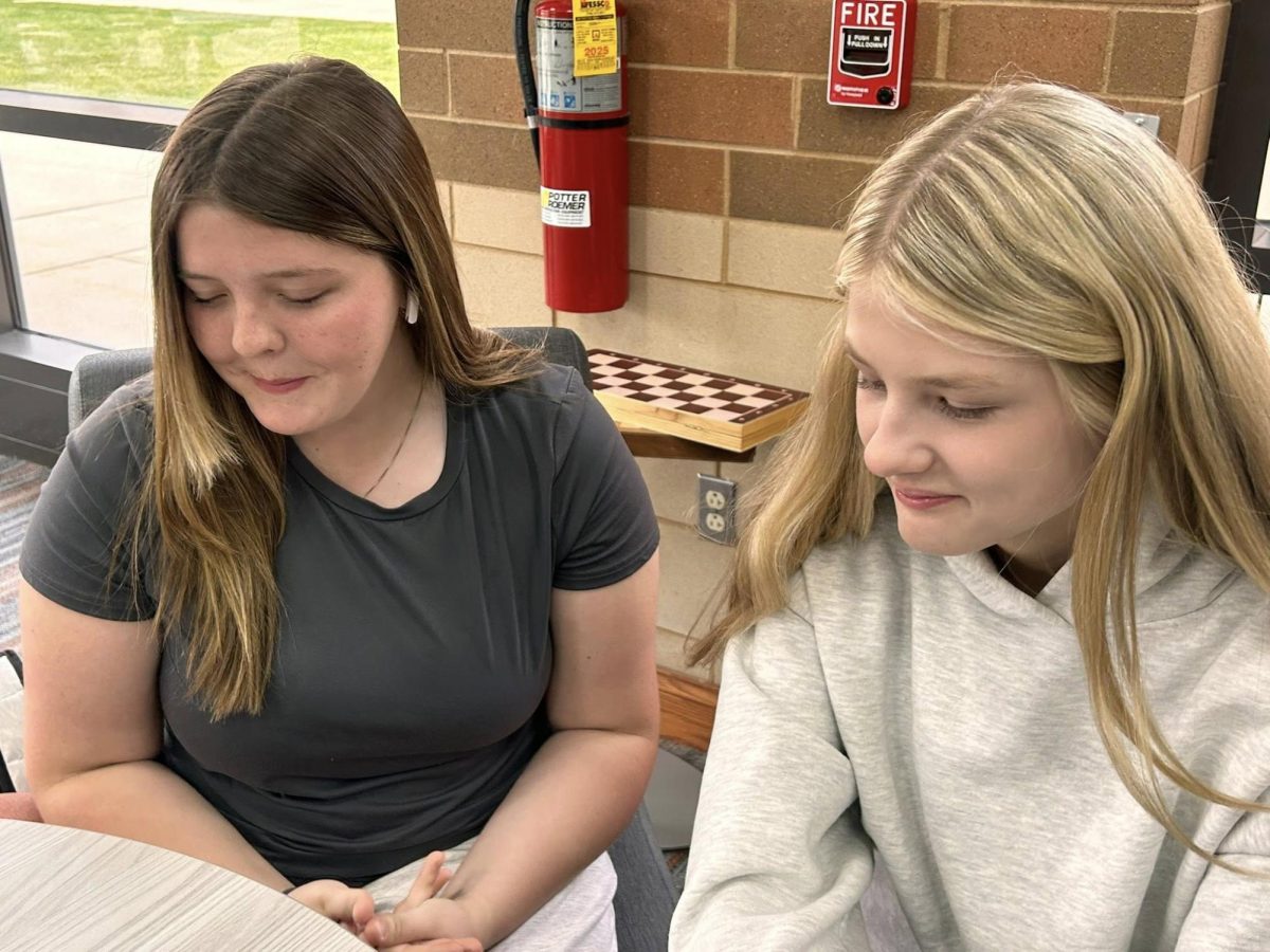 Two students listening to music in the library while studying.  